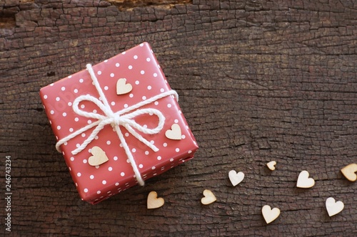 Elegant red gift box decorated with mini heart figure on wood background, valentine love present concept