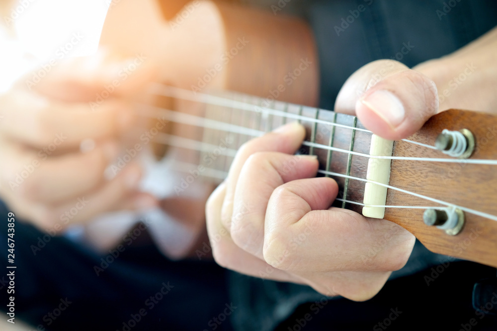 A man, he is playing ukulele brown happily in the park on holiday.