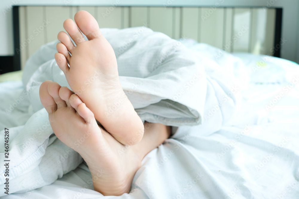 Beautiful legs and feet She sleeps happily under a blanket in her bedroom at home. Beautiful legs and feet She sleeps happily under a blanket in her bedroom at home.