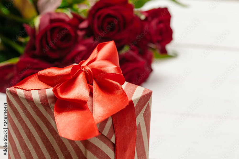 A bouquet of red roses, gift and hearts on table. Concept Women's Day or St. Valentine. Copy space A bouquet of red roses, gift and hearts on table. Concept Women's Day or St. Valentine. Copy space