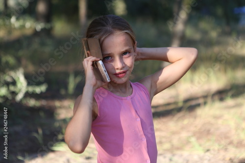 on the background of nature a little girl emotionally talking on the phone with a friend