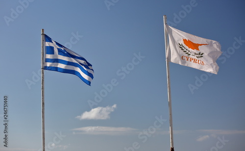 Flags of Greece and republic of Cyprus on flagpoles next to each other wave on wind