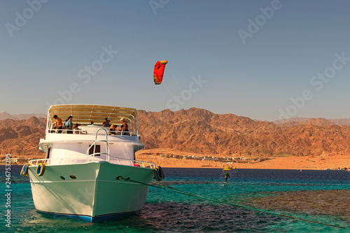 Obraz na plátně Dahab, Egypt-JANUARY 06, 2019: Kiteboarder enjoying surfing in blue water near the moored yacht