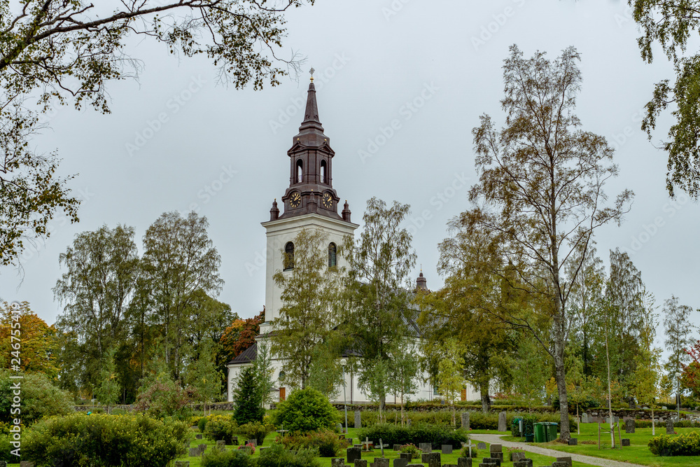 Church in Sweden with colorful autumn trees and a cemetery in front