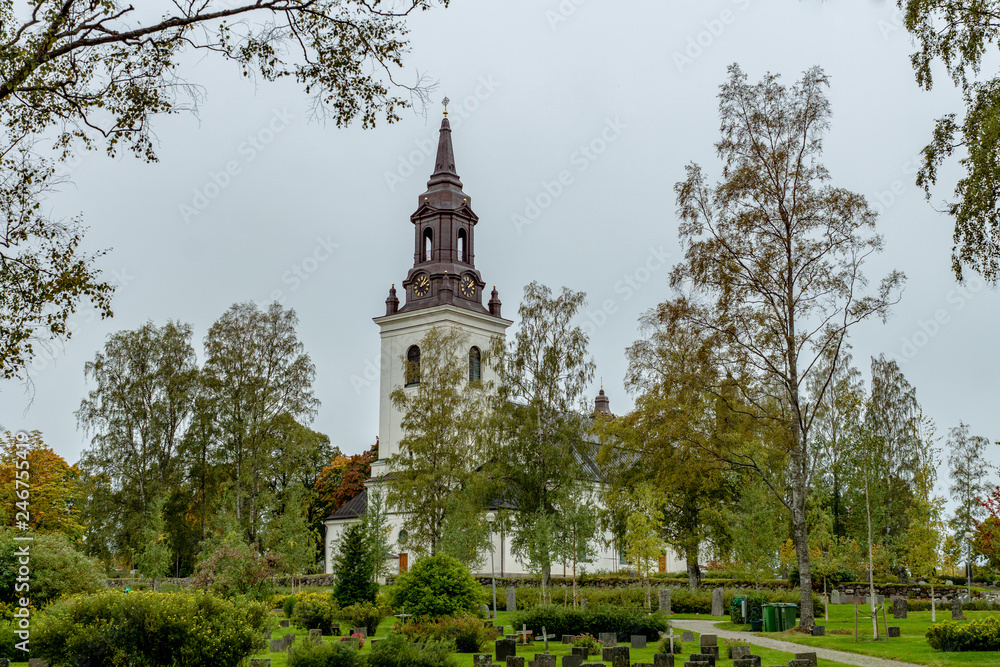 Church in Sweden with colorful autumn trees and a cemetery in front Church in Sweden with colorful autumn trees and a cemetery in front