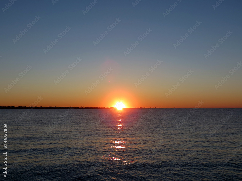 Beautiful sunset over the Adriatic sea,  berth in Rimini, Italy, Europe. The hot  sun sets in the warm water.