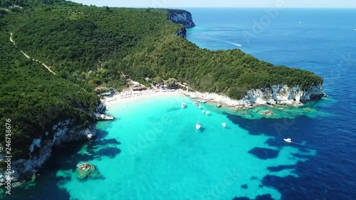 Aerial drone video of tropical paradise turquoise beach of Voutoumi with sail boats docked in island of Antipaxos, Ionian, Greece photo