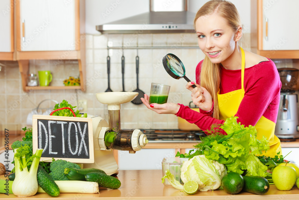 Woman looking at vegetable juice through magnifying glass Woman looking at vegetable juice through magnifying glass
