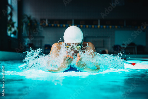 Professional woman swimmer swim using breaststroke technique on the dark background photo