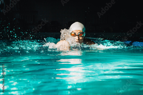 Professional woman swimmer swim using breaststroke technique on the dark background