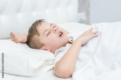 Obraz na plátně Boy is sleeping on the bed with his mouth open, snoring