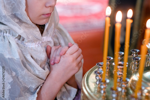 Close up little girl with a candle prays in church