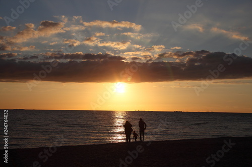 silhouettes d'une famille sur la plage au coucher du soleil