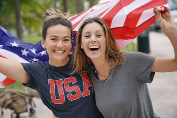 Two dynamic young friends proudly flying the American flag together outdoors