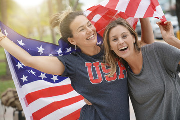 Two dynamic young friends proudly flying the American flag together outdoors