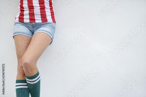 Waist down cut off of slim young woman in strippy top and knee socks on white background