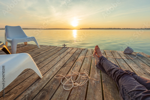 Man relaxing on footbridge with naked foot. Concept of waiting for summer.
