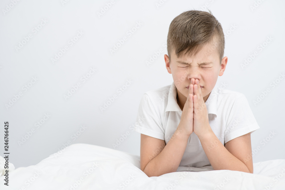 Young boy praying in bedroom before going to bed Young boy praying in bedroom before going to bed