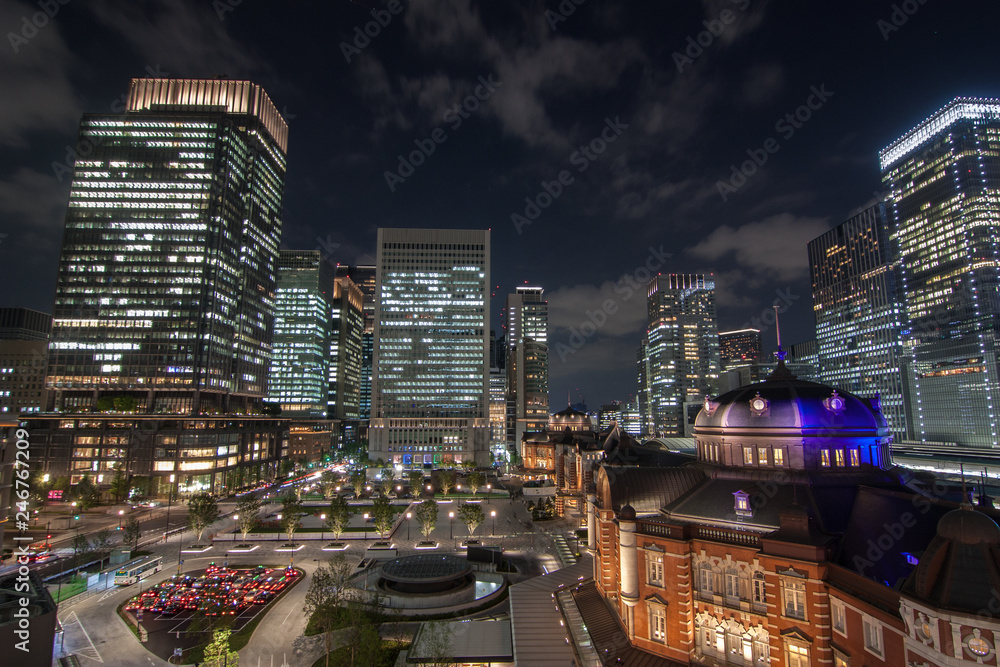 Night view at Tokyo Station in Tokyo, Japan. There are many skyscrapers around and cars parking.  