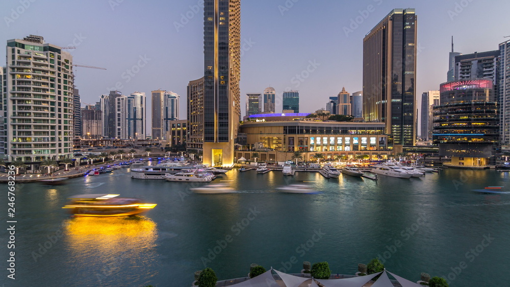 Fototapeta premium Aerial vew of Dubai Marina with shoping mall, restaurants, towers and yachts day to night timelapse, United Arab Emirates.