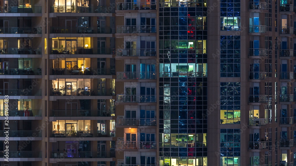 Obraz premium Glowing windows in multistory modern glass residential building light up at night timelapse.