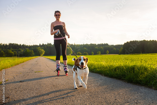 Girl skating with Beagle dog outdoors in nature. photo