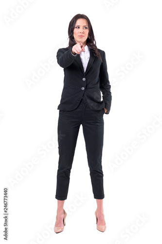 Distracted formal business woman pointing finger at camera but looking away. Full body isolated on white background. 