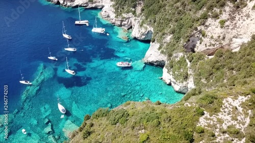 Aerial bird's eye view video taken by drone of caves  and boats docked in caribbean tropical beach with turquoise - sapphire waters and caves forming a blue lagoon photo