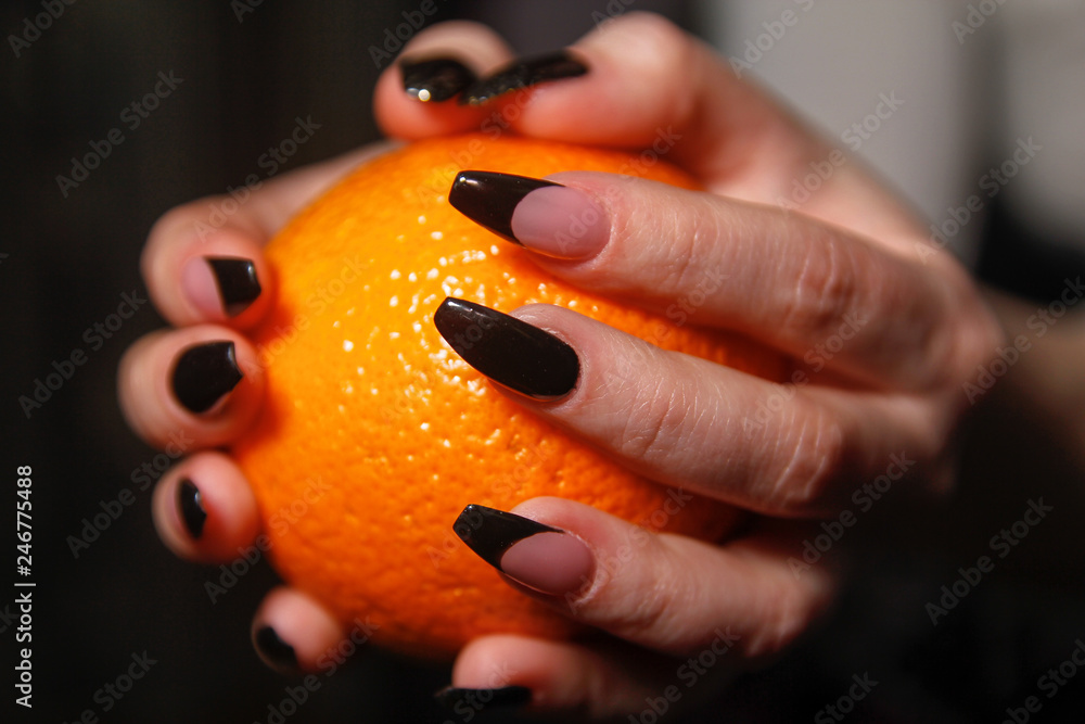 Women's hands with nail arts on nails holding orange fruit Women's hands with nail arts on nails holding orange fruit