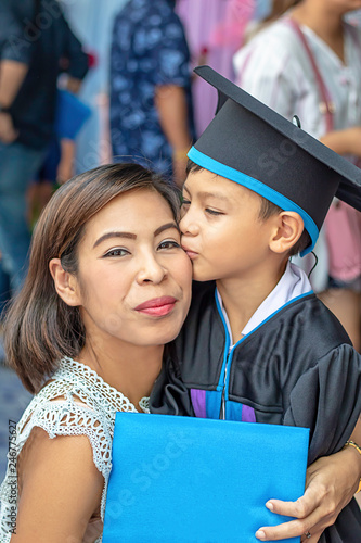 Portrait son graduated from kindergarten kissing mother