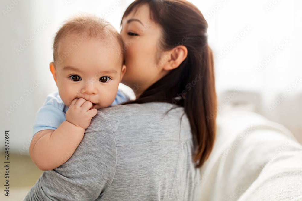 family and motherhood concept - close up of happy young asian mother kissing little baby son at home family and motherhood concept - close up of happy young asian mother kissing little baby son at home