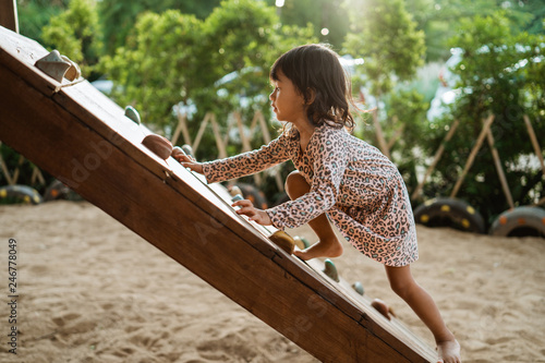 Fotografía from a side view a girl trying climb use her legs and her arm to hold a pinch