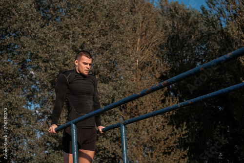 Powerful adult man wearing black sportswear performing kettlebell pushups in modern gym