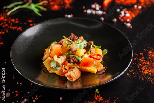 The concept of Spanish cuisine. Spanish salad with chorizo sausage, orange, tomato, baguette, tarragon, olive oil. A glass of cool wine on the table. background image. copy space