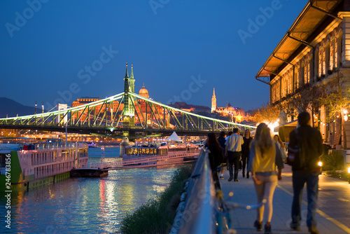 Waterfront promenade in Budapest by night, Liberty bridge, walking people photo