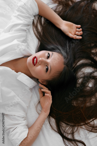 Beautiful woman with long hair, red lips makeup in white shirt