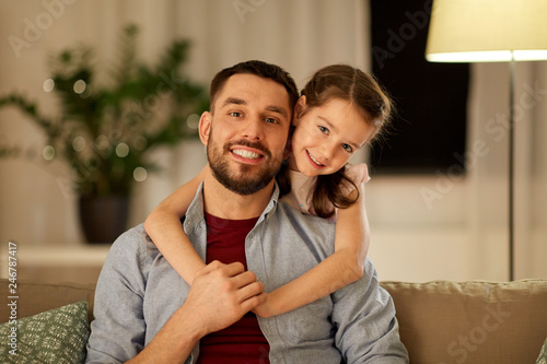 family, fatherhood, leisure and people concept - happy smiling father and little daughter hugging at home in evening