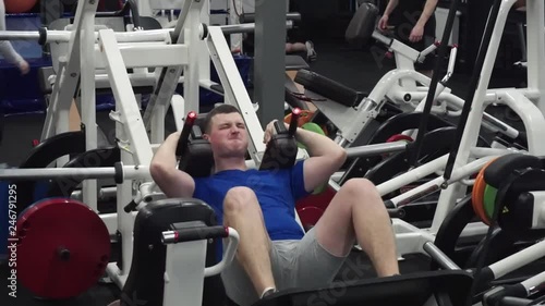 Office manager first day in the gym trying Hack leg press squat. Face expression shows it is very hard for him