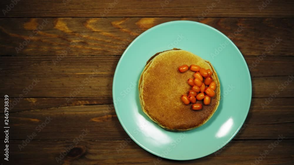 Top view on azure plate with appetizing pancakes and orange sea-buckthorn berries on a wooden table, the camera moves from left to right. Top view on azure plate with appetizing pancakes and orange sea-buckthorn berries on a wooden table, the camera moves from left to right.