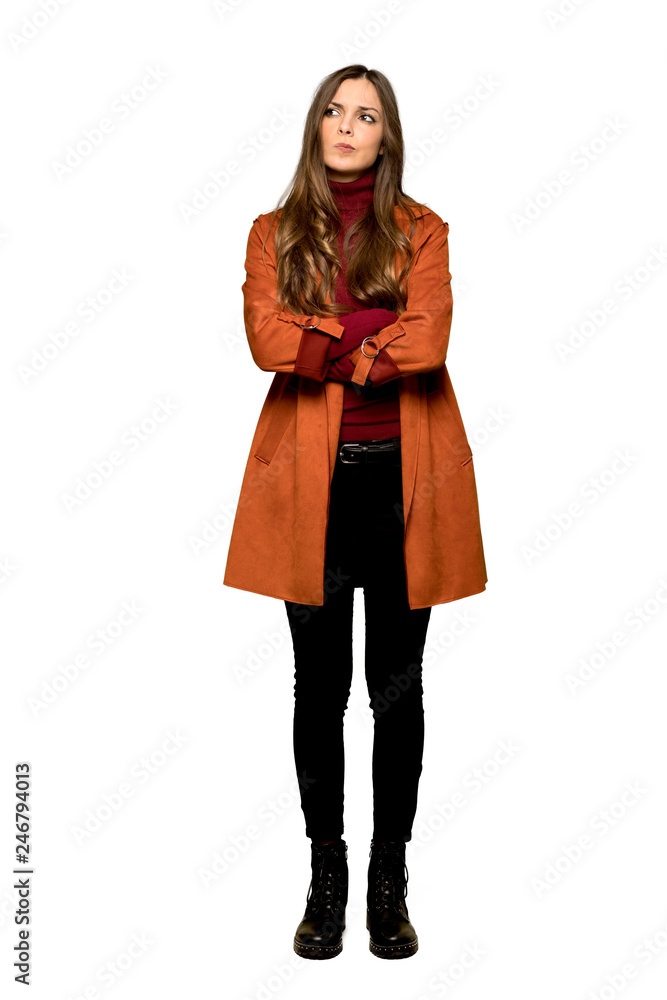 Full-length shot of Young woman with coat feeling upset on isolated white background