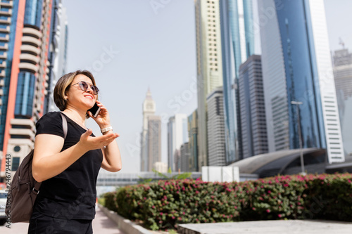 Adult woman talking with mobile phone in city street. © 1001color