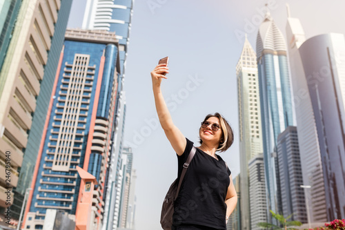 Adult tourist taking selfie between skyscraper.