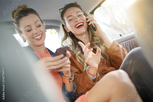Tableau sur toile Two attractive friends talking and laughing in casual evening wear in back of ta