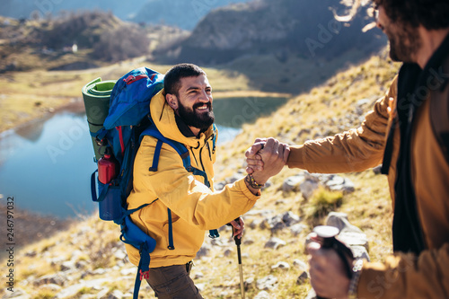 Fotografija Helping hand - hiker man getting help on hike happy overcoming obstacle