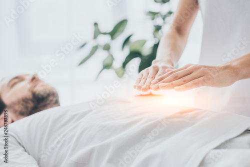 cropped shot of man receiving reiki treatment on stomach