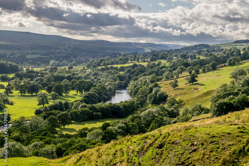 a valley with storm clouds and sheep in the fields. 