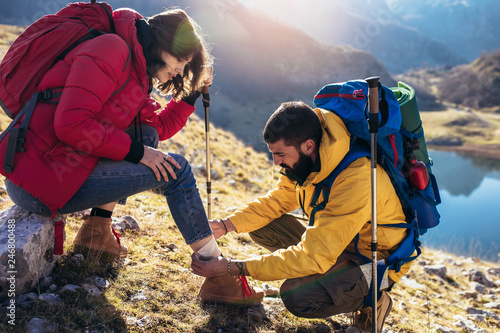 A woman has sprained her ankle while hiking, her friend uses the first aid kit to tend to the injury photo