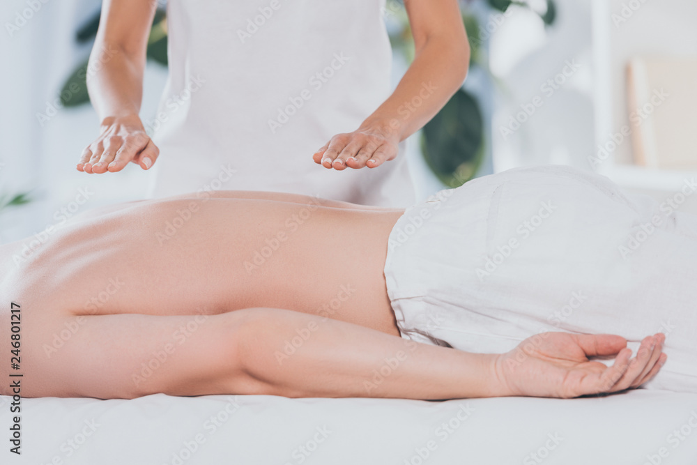 cropped shot of bare-chested man receiving reiki healing treatment on back cropped shot of bare-chested man receiving reiki healing treatment on back