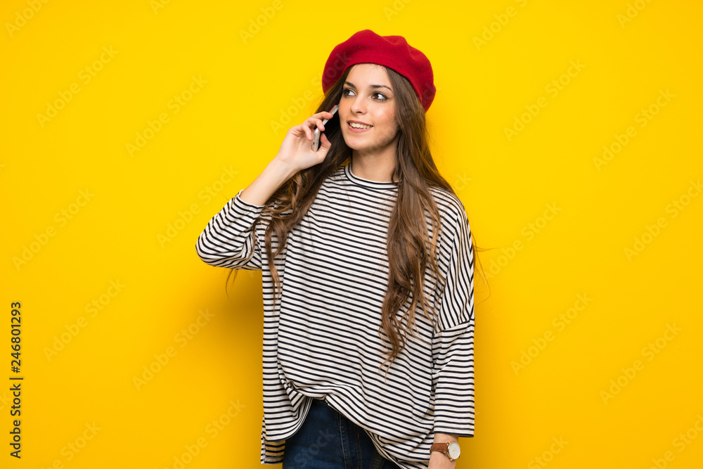 Girl with french style over yellow wall keeping a conversation with the mobile phone Girl with french style over yellow wall keeping a conversation with the mobile phone