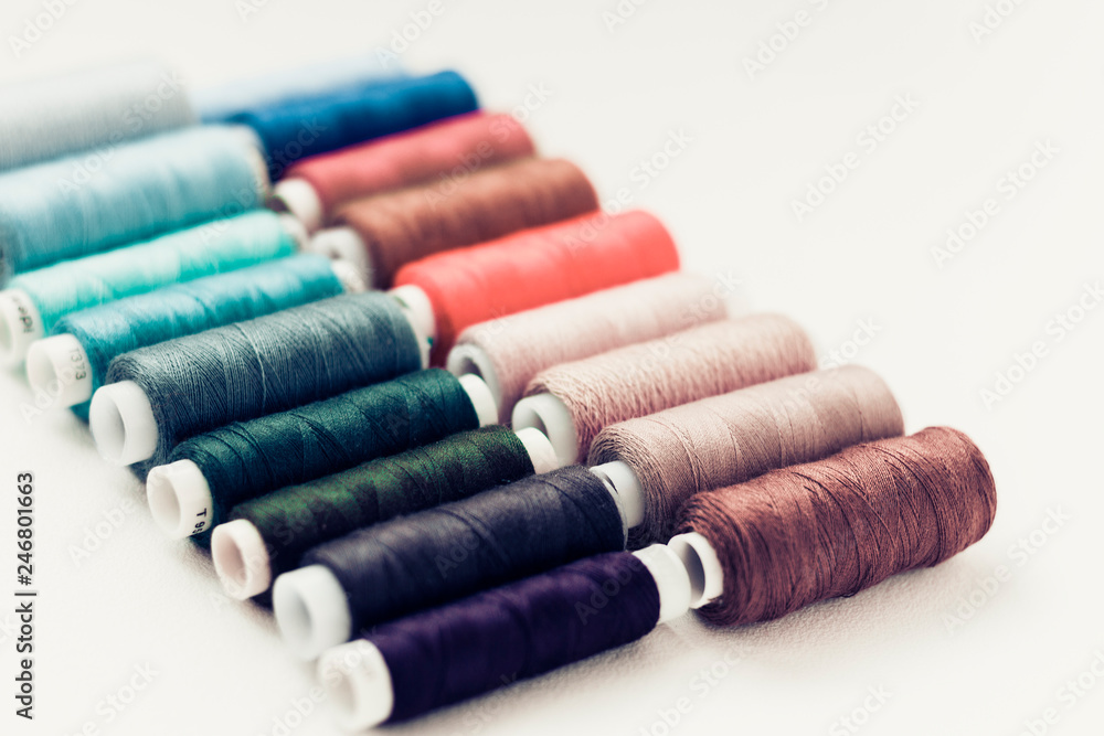 Colored sewing thread coils on white background with copy space for text. Colored sewing thread coils on white background with copy space for text.